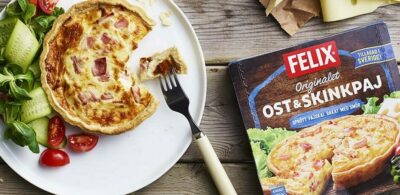 Ost- och skinkpaj på tallrik med sallad och förpackning bredvid