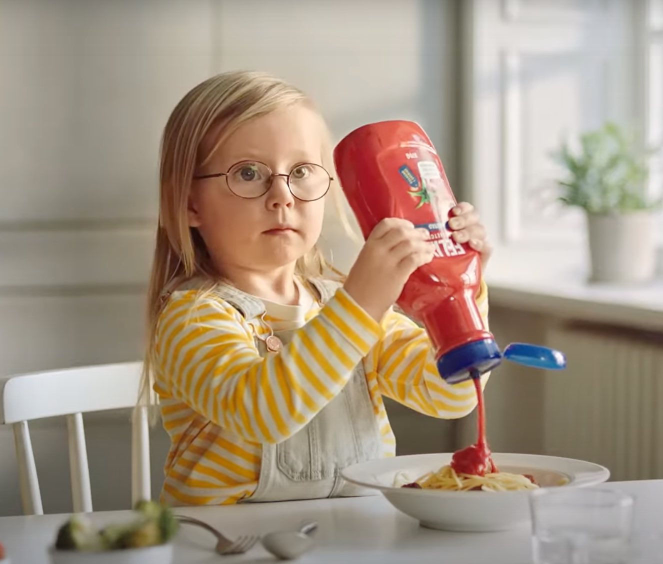 Flicka häller Felix osötade ketchup över tallrik med spagetti.