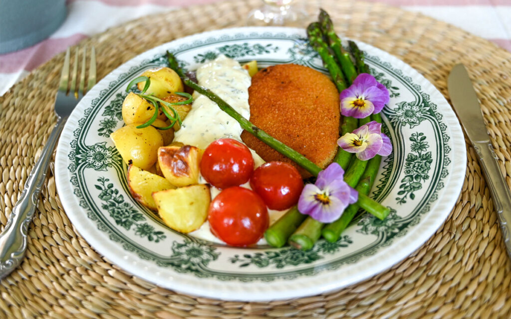 Tallrik med Felix vegetariska schnitzel med örtsås, nypotatis och sparris.