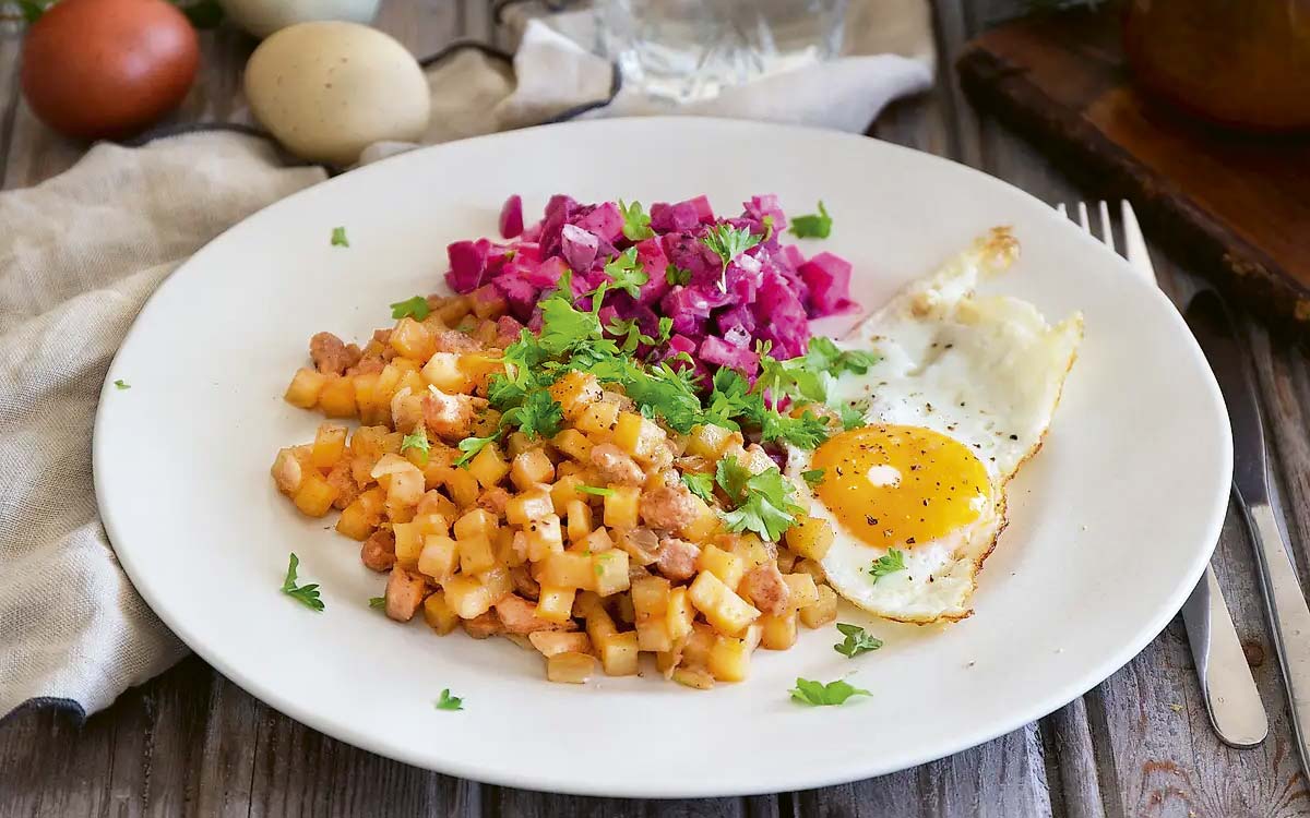 Tallrik med gräddstuvad vegetarisk pytt i panna med rödbetssallad och stekt ägg.