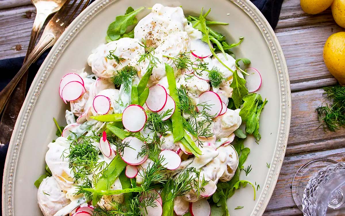 Fat med krämig färskpotatissallad med rädisor och sockerärtor.