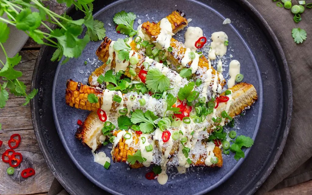 Tallrik med grillad majs toppad med koriander, chili och Felix drizzlad bearnaisesås.