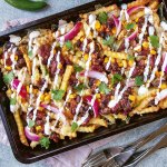 En plåt med dirty taco fries toppad med bönsalsa, picklad rödlök och koriander.