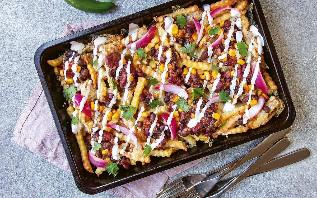 En plåt med dirty taco fries toppad med bönsalsa, picklad rödlök och koriander.