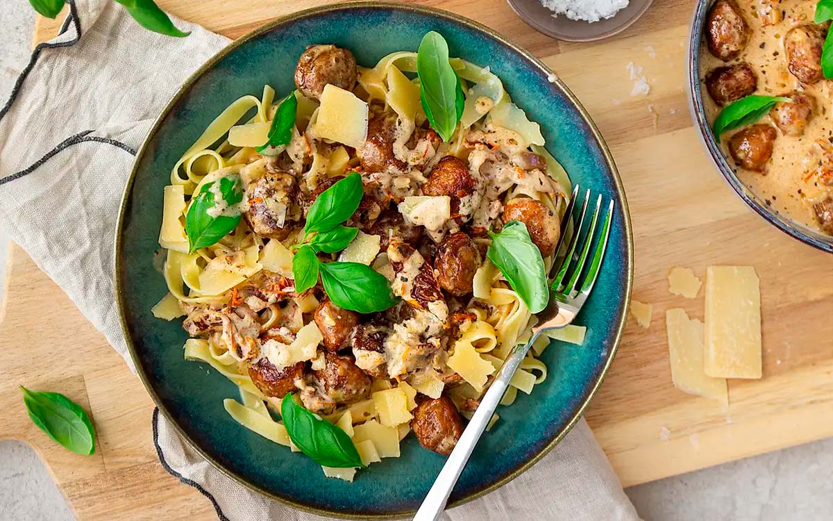 Tallrik med pasta och marry me meatballs toppad med parmesan och färsk basilika.