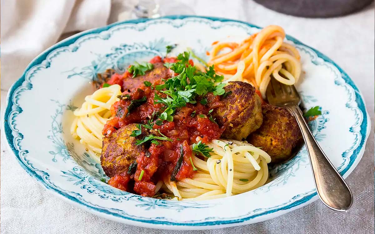 Tallrik med pasta med vegobullar i mustig tomatsås.
