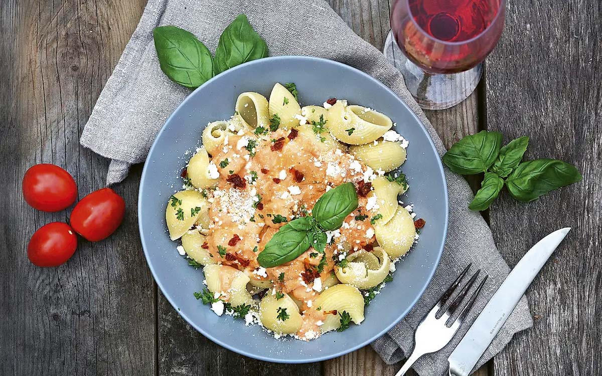 Tallrik med pasta med rosa baconsås, basilika och parmesan.