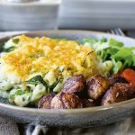 Tallrik med mac n cheese, sallad och små delikatessköttbullar.