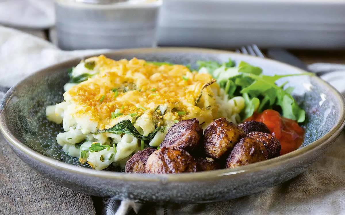 Tallrik med mac n cheese, sallad och små delikatessköttbullar.