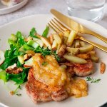 Tallrik med stekta fläskkotletter med pommes och sallad.