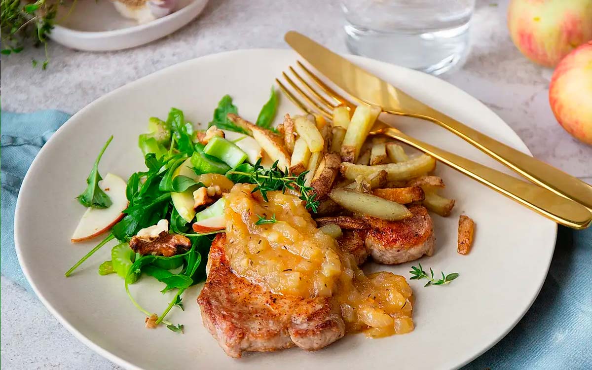 Tallrik med stekta fläskkotletter med pommes och sallad.