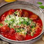 Tallrik med italienska köttbullar i tomatsås toppad med basilika och parmesan.