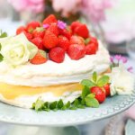 Somrig jordgubbstårta med marängbottnar, grädde, vit choklad och äpplemos toppad med färska jordgubbar.