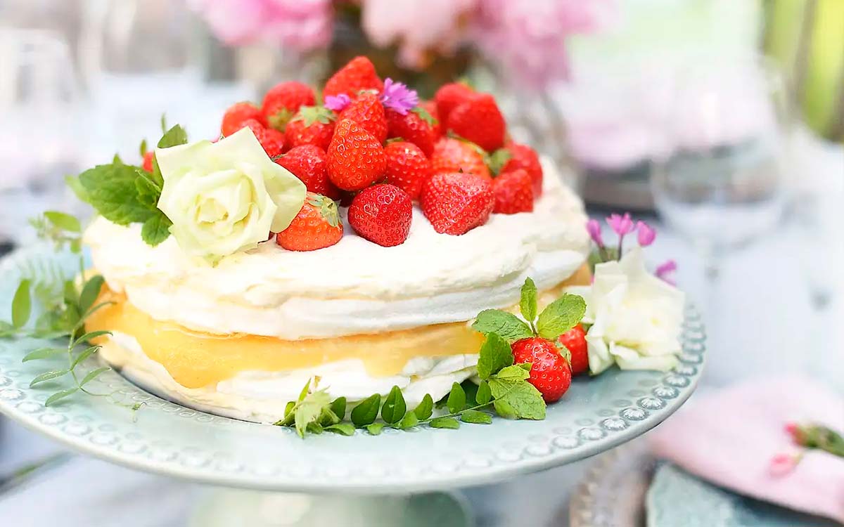 Somrig jordgubbstårta med marängbottnar, grädde, vit choklad och äpplemos toppad med färska jordgubbar.