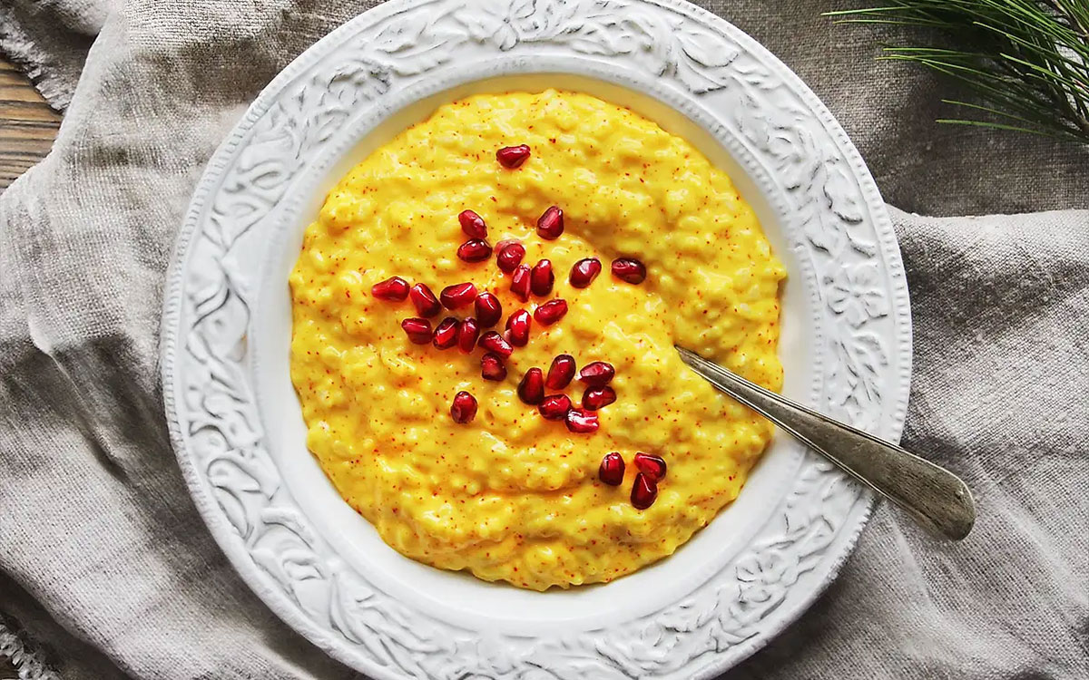 Tallrik med saffransgröt med apelsin toppad med granatäpplekärnor.
