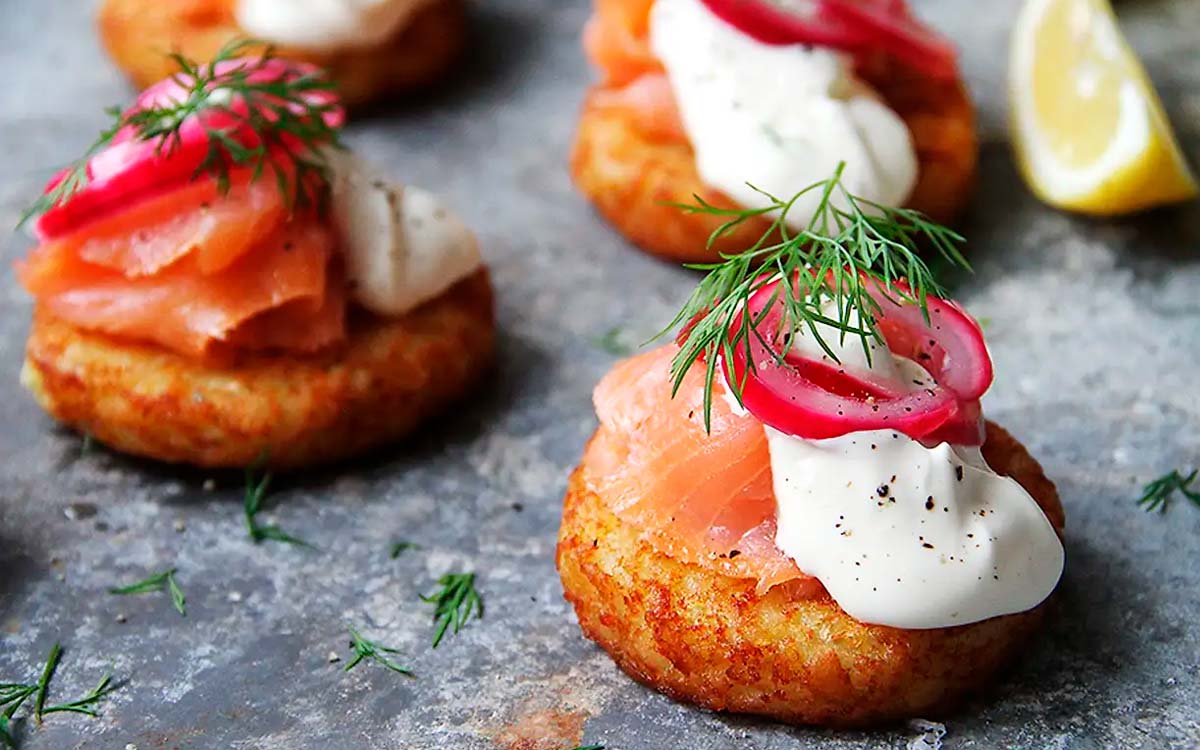 potatisbullar som snittar med lax, creme fraiche, picklad rödlök, dill och citron.