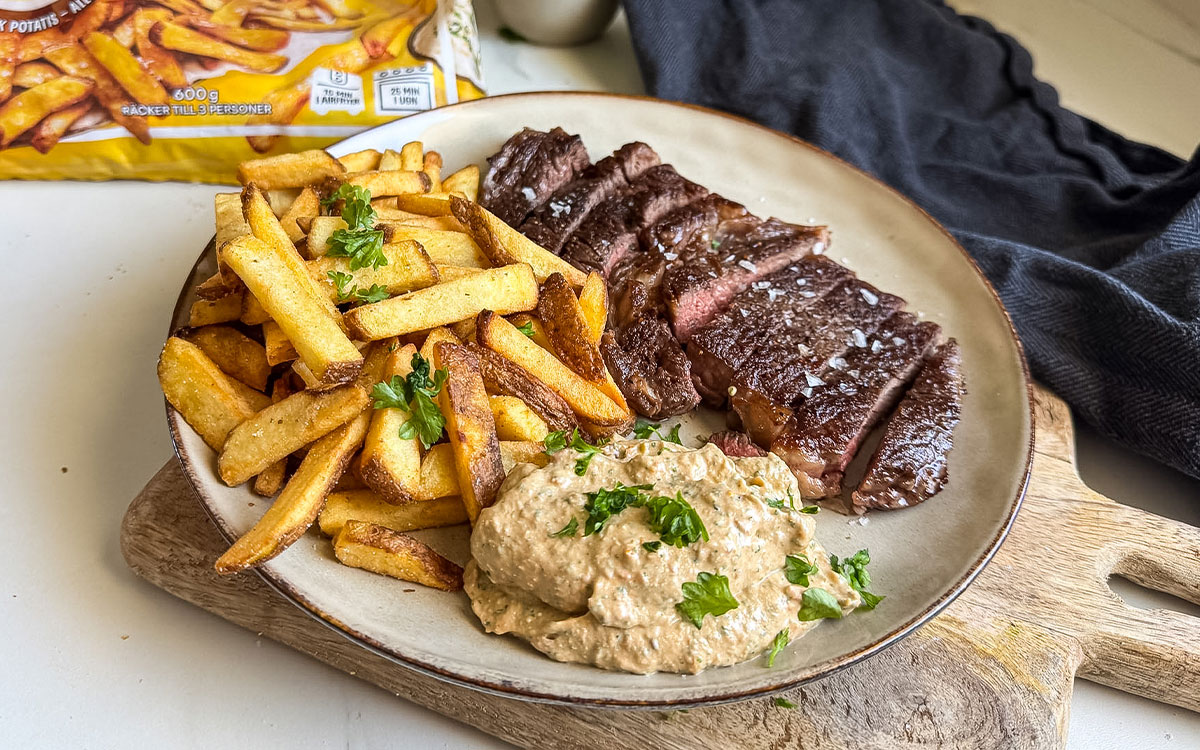 Tallrik med grillat kött och Felix krispiga pommes tillsammans med en röra gjord på fetaost, soltorkade tomater, creme fraiche, basilika och vitlök.