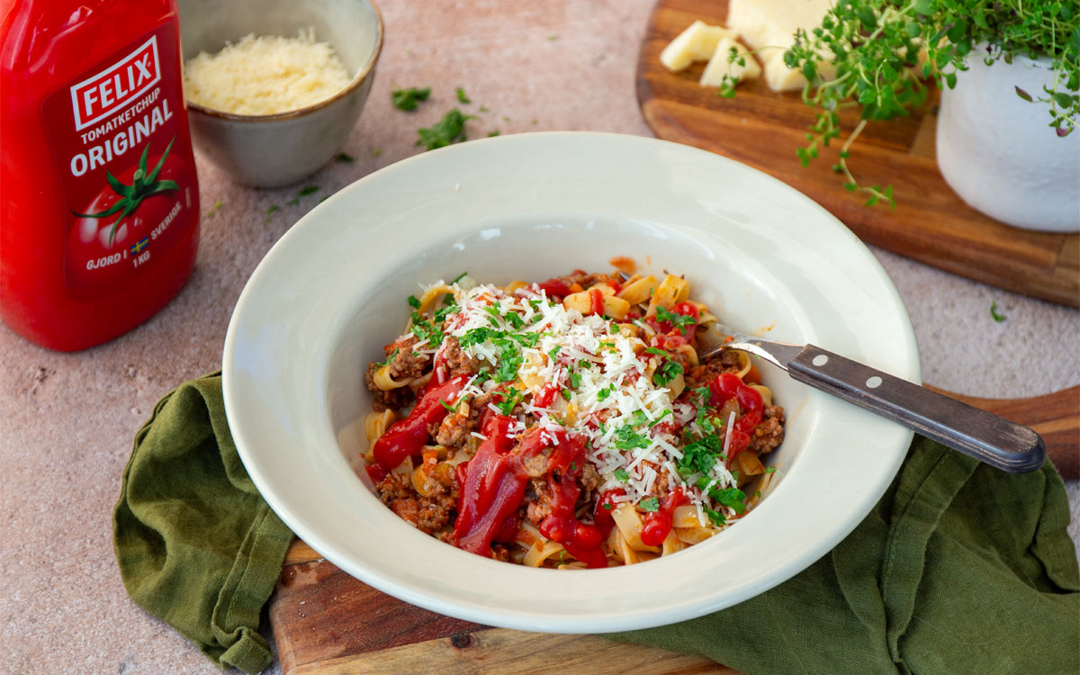 Tallrik med pasta bolognese med parmesan, persilja och Felix tomatketchup.