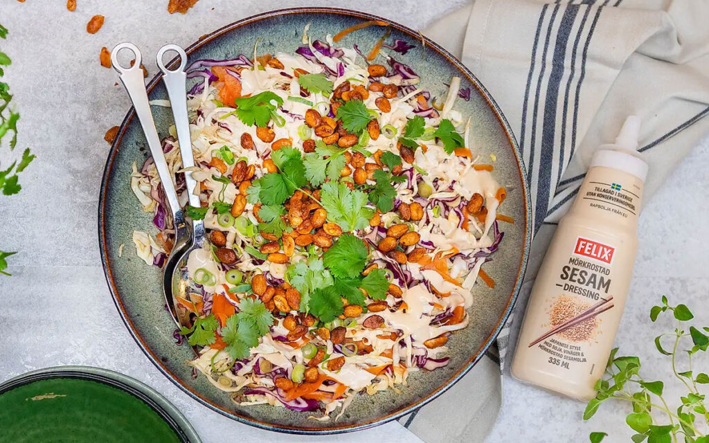 Skål med asiatisk kålsallad med chilirsotade jordnötter toppad med färsk koriander samt Felix mörkrostade sesamdressing.