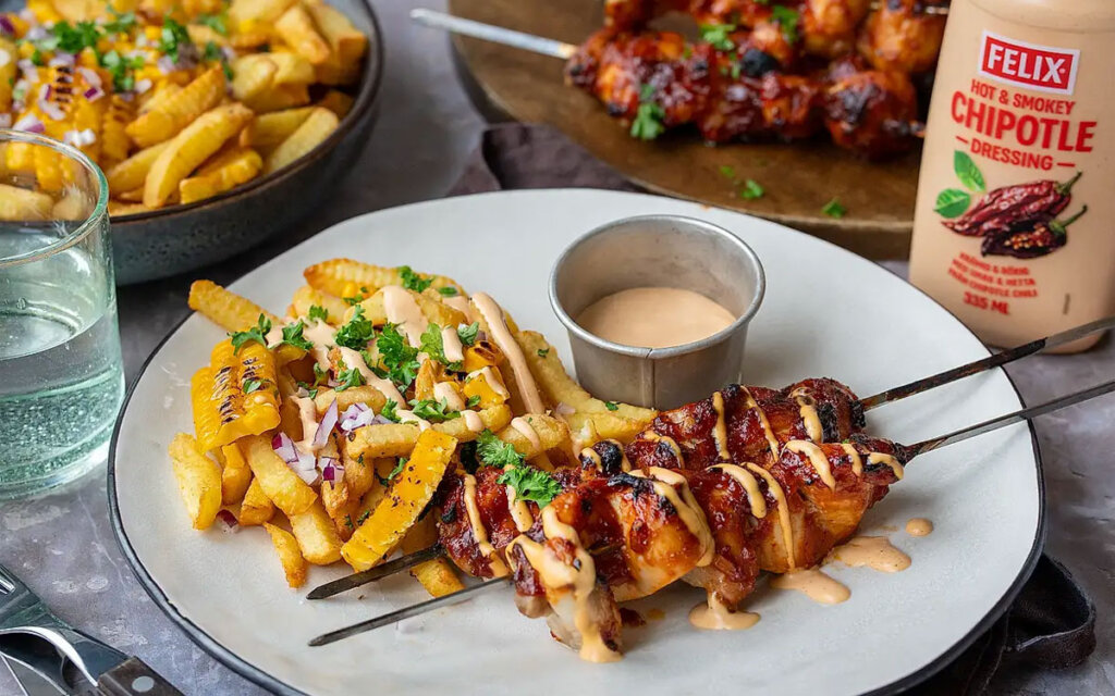 Tallrik med grillade kycklingspett, pommes och Felix Hot Chipotle dressing.