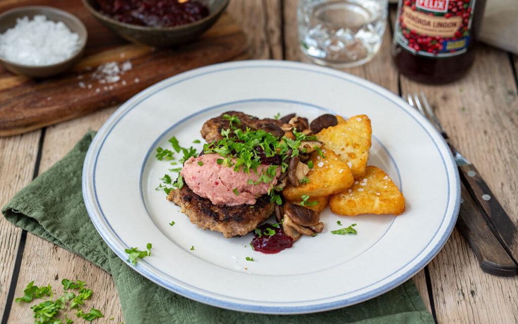Tallrik med pannbiffar, rösti, svamp och brynt lingonsmör.