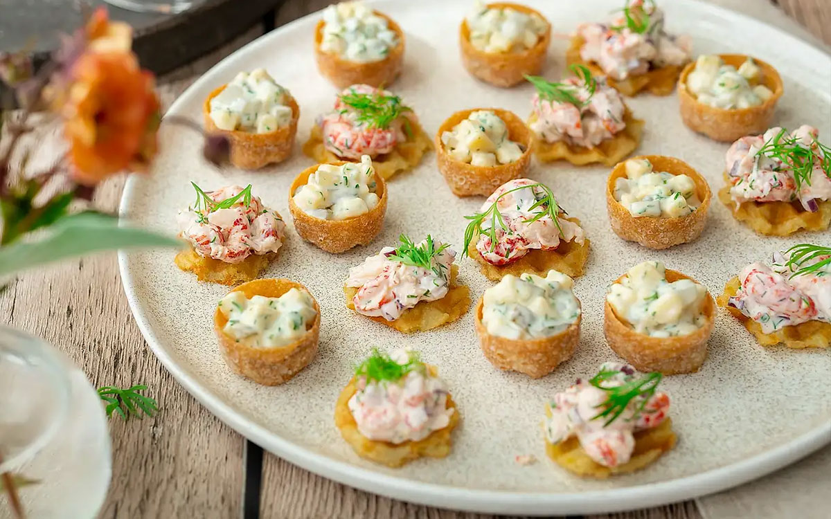 Ett fat med snittar gjorda av kroketter och krustader fyllda med kräftskagen och västerbottenröra.