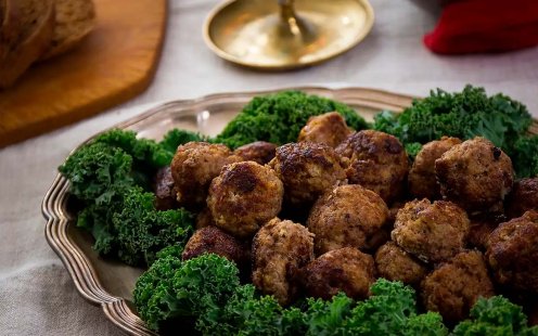 Fat med klassiska julköttbullar kantade med grönkålsblad.