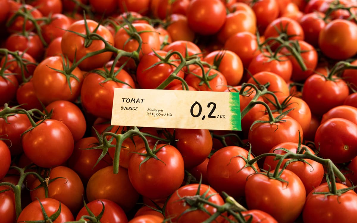hög av tomater med skylt med klimatavtryck