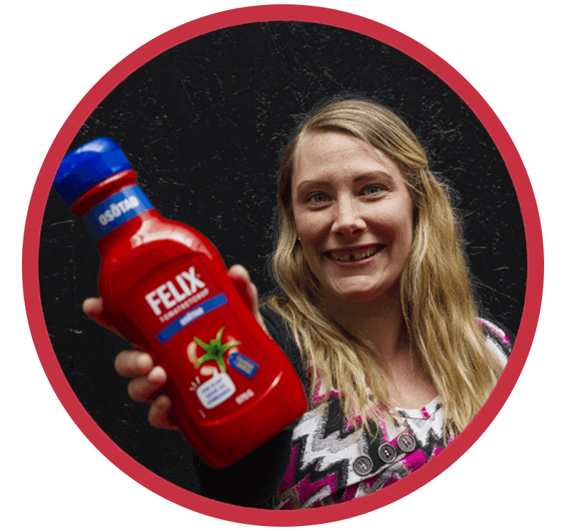 Glad tjej som håller upp en flaska med Felix osötade ketchup