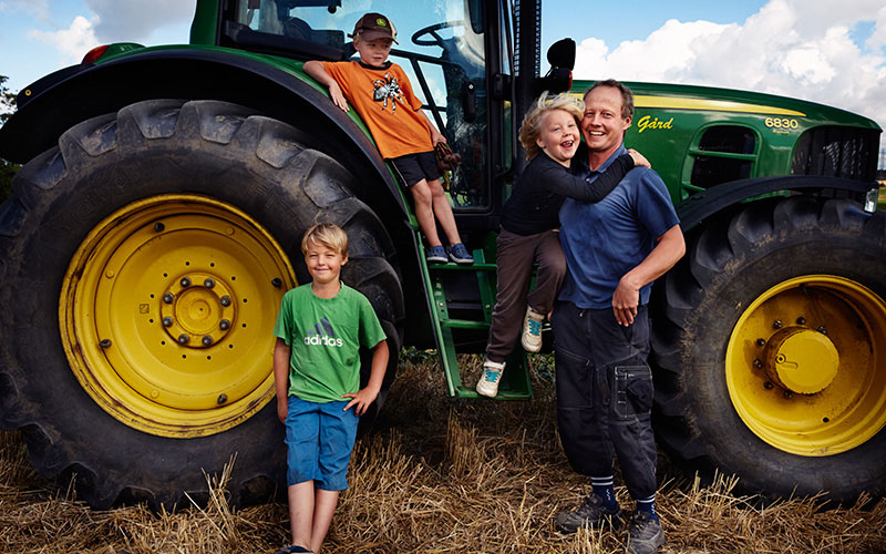 Pappa med tre barn framför en traktor