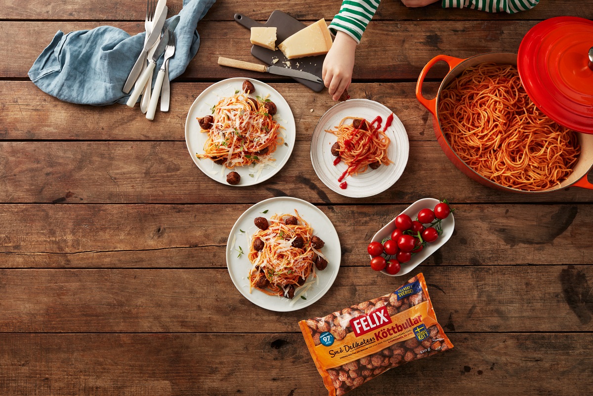 Bord med tallrikar med spagetti och köttbullar med tomatketchup.
